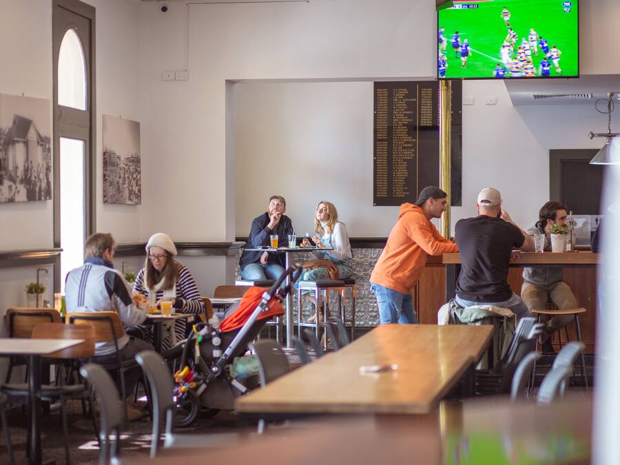 A restaurant with tables and chairs, a counter, and a television mounted on the wall.