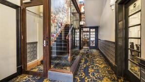 A hallway with patterned carpet, a staircase, and a door leading to a room. - Ramsgate Hotel by Nightcap Social (Henley Beach)
