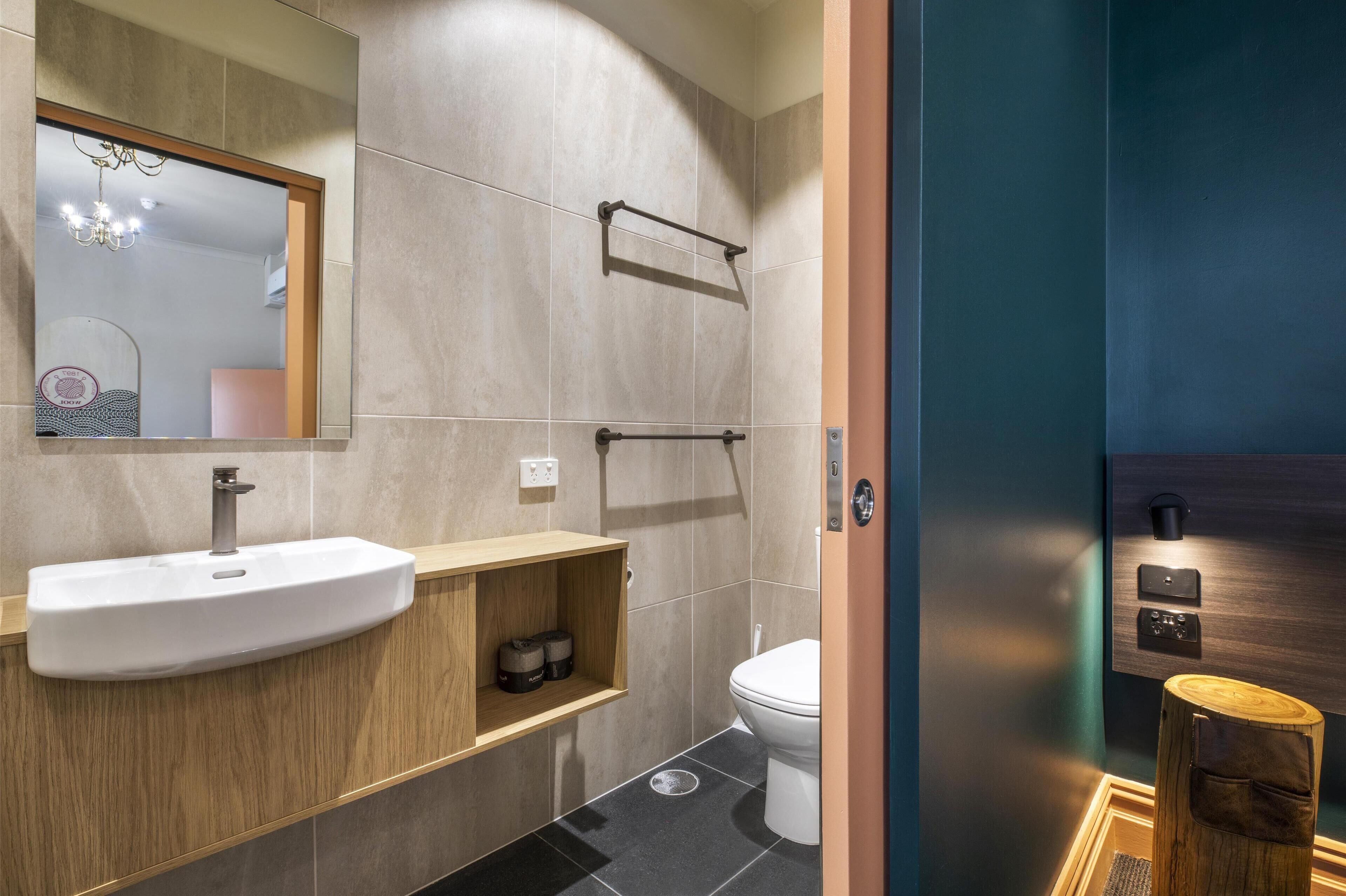 Un baño moderno con lavamanos, espejo, toallero y retrete.