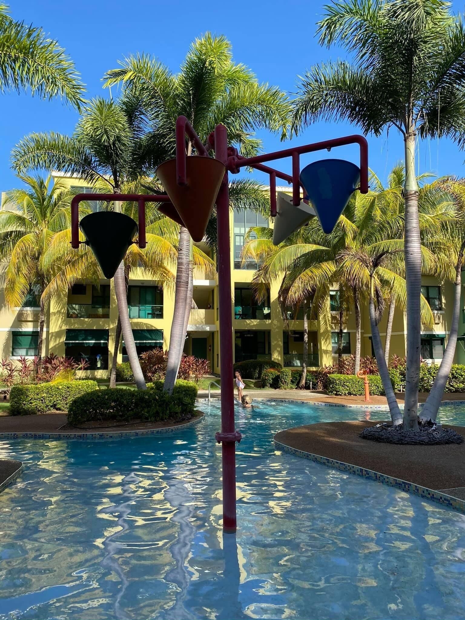 A pool area with a water feature and palm trees.