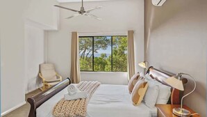 A bedroom with a bed, a chair, a desk, a lamp, a ceiling fan, and a window with a view. - Eagle Vista—Beachside Bliss with Bushland Serenity (Eagle Bay)