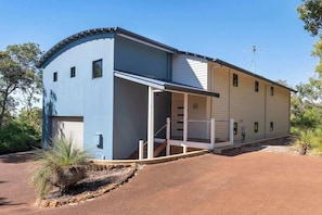 A two-story building with a curved facade, a covered porch, and a garage.