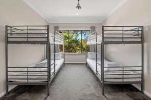 A room with bunk beds, a large window, and a carpeted floor.