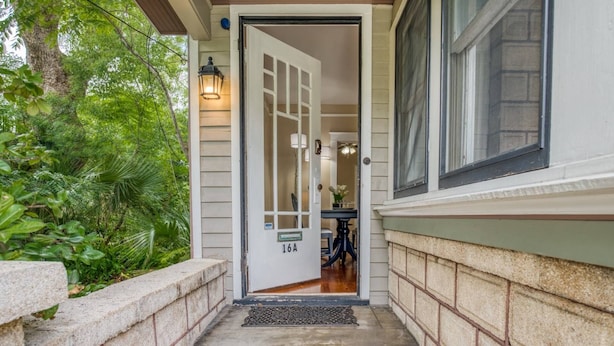 A house entrance with a door labeled '10A', a small table with a vase, and a window to the right.