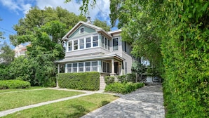 A two-story house with a front porch, a driveway, and a well-maintained lawn.