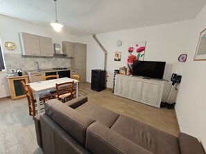 A compact living space with a kitchenette, dining area, and a sofa.