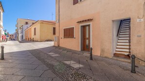 A narrow street with buildings, a cobblestone path, and a wooden staircase leading to a door.
