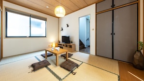 A traditional Japanese room with tatami flooring, a low table with cushions, a television, and sliding doors. - Urban Stay Shinagawa (Tokyo)