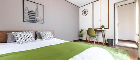 Un dormitorio con una cama, un escritorio, una silla y una alfombra verde.