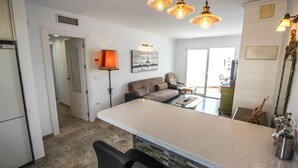 A modern kitchen with a central island, pendant lighting, and a dining area with a sofa and table. - Angel - sea view apartment in Calpe (Calpe)