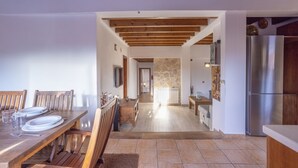 A spacious kitchen with a wooden dining table, a built-in refrigerator, and a stone wall in the background.
