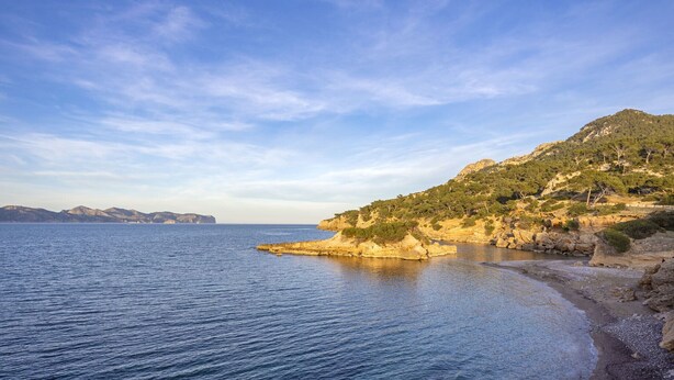 A coastal landscape with a rocky beach and clear blue sea.