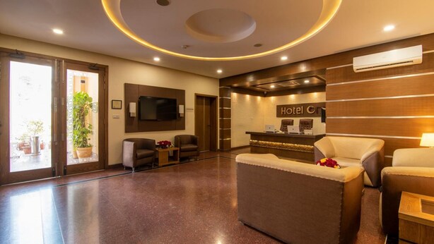 A hotel lobby with a reception desk, seating area, and a large TV screen. - Hotel One Tariq Road Multan (Multan)