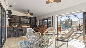 A spacious living area with a bar, seating, and a large TV.