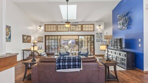 A spacious living room with a large brown sofa, a ceiling fan, and a television on a cabinet.