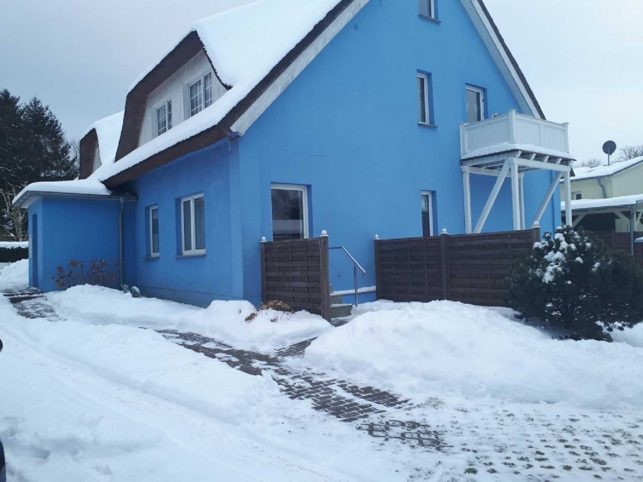 Una casa azul con entrada de ladrillo, un pequeño porche y una puerta de garaje blanca.