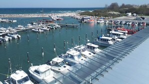 Un port de plaisance où sont amarrés différents types de bateaux, une jetée qui s’avance dans l’eau et une vue dégagée sur la côte.