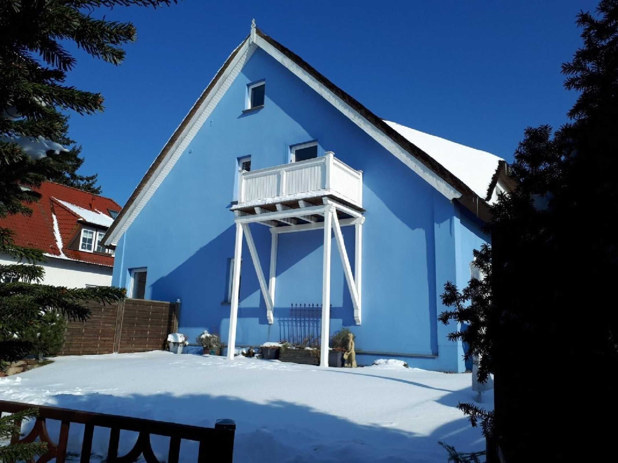 A blue building with a white balcony, surrounded by snow.