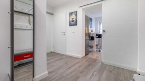 Un intérieur moderne avec une porte coulissante, un coin cuisine et un couloir menant à une autre pièce.