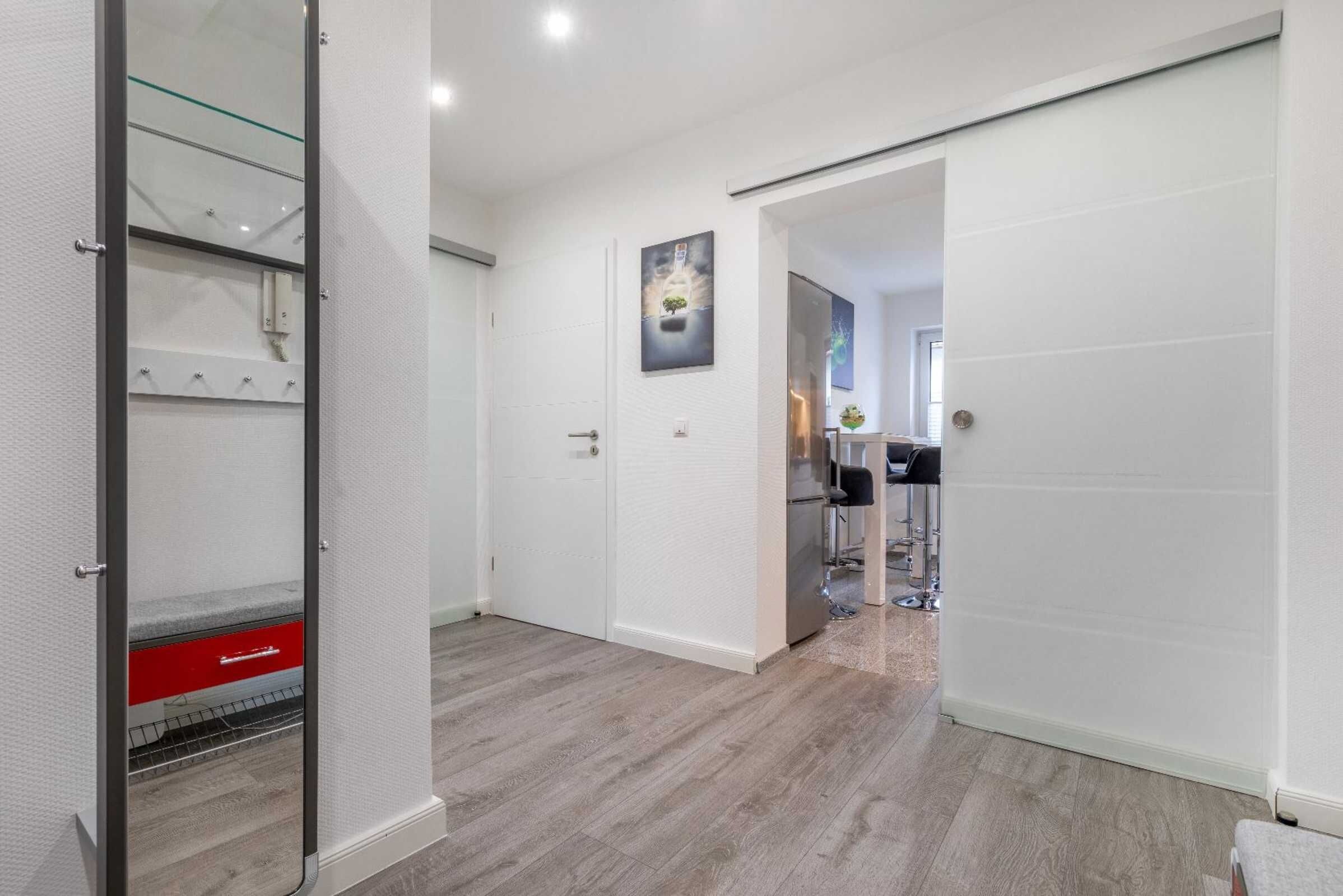 A modern interior with a sliding door, a kitchen area, and a hallway leading to another room.