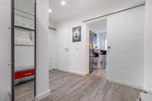 A modern interior with a sliding door, a kitchen area, and a hallway leading to another room.