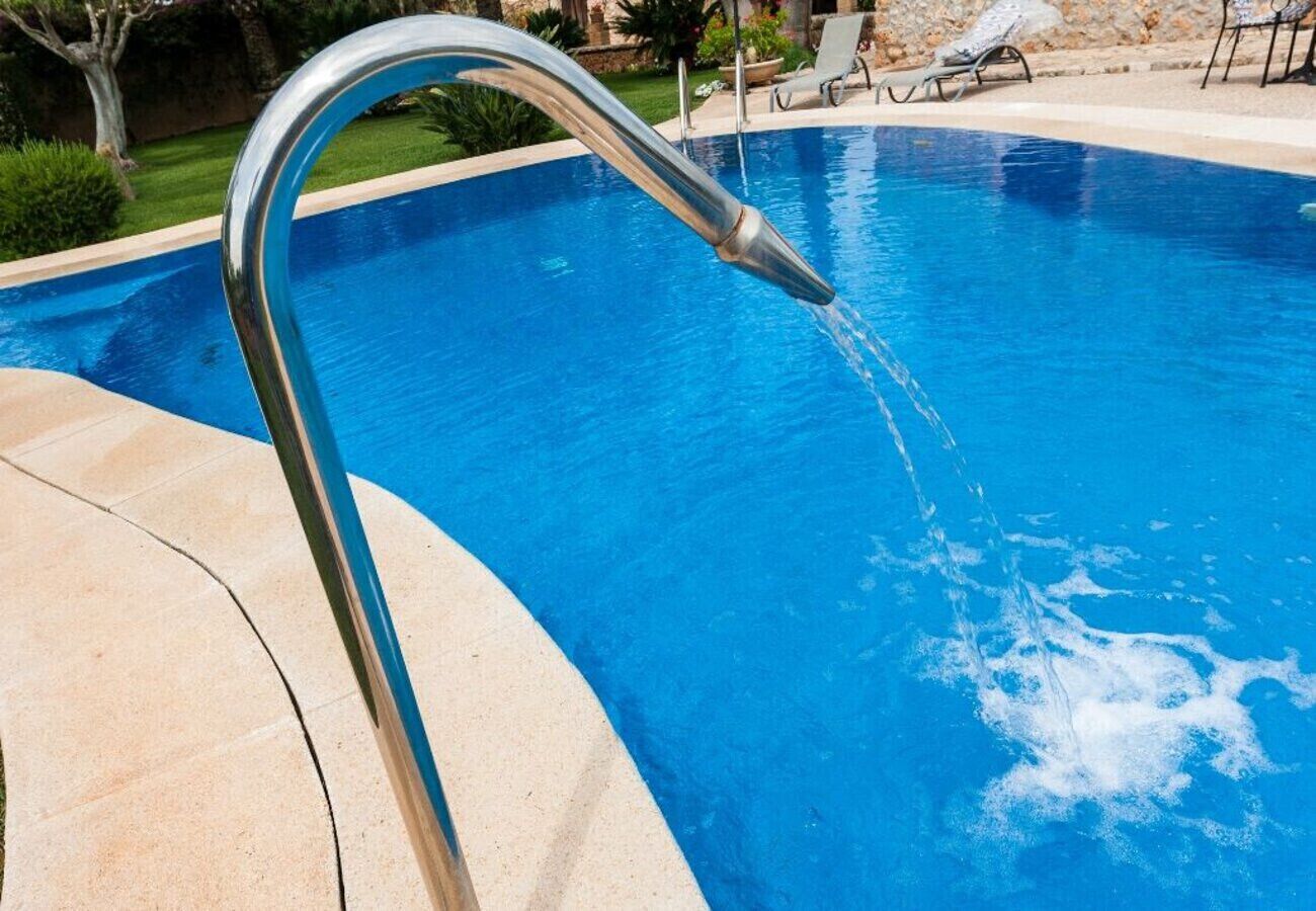 A swimming pool with a metal faucet and a stone border.