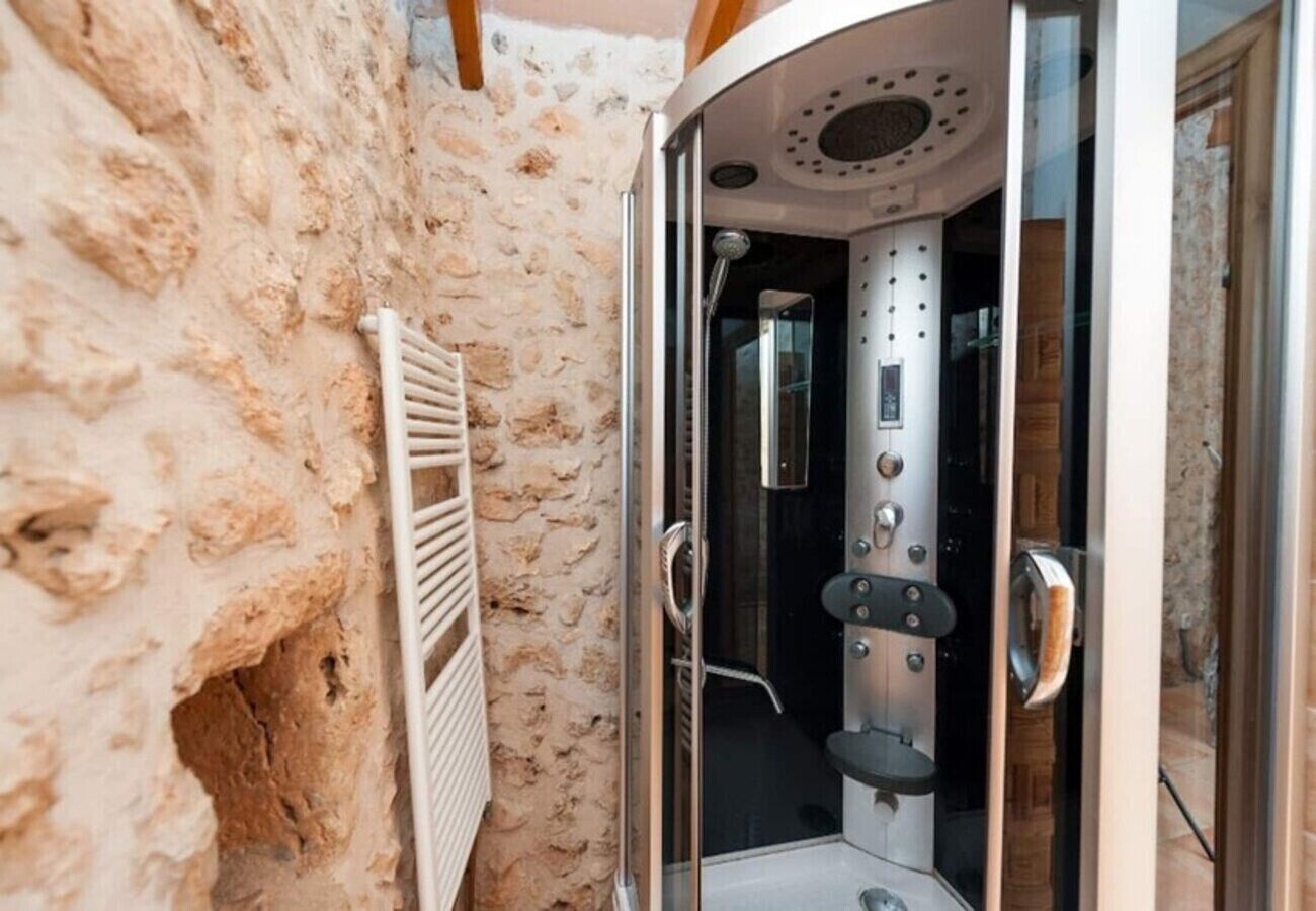 A stone-walled bathroom with a glass-enclosed shower stall.
