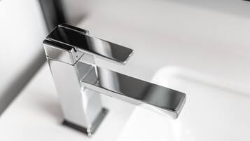 A chrome faucet with a modern design, mounted on a white countertop.