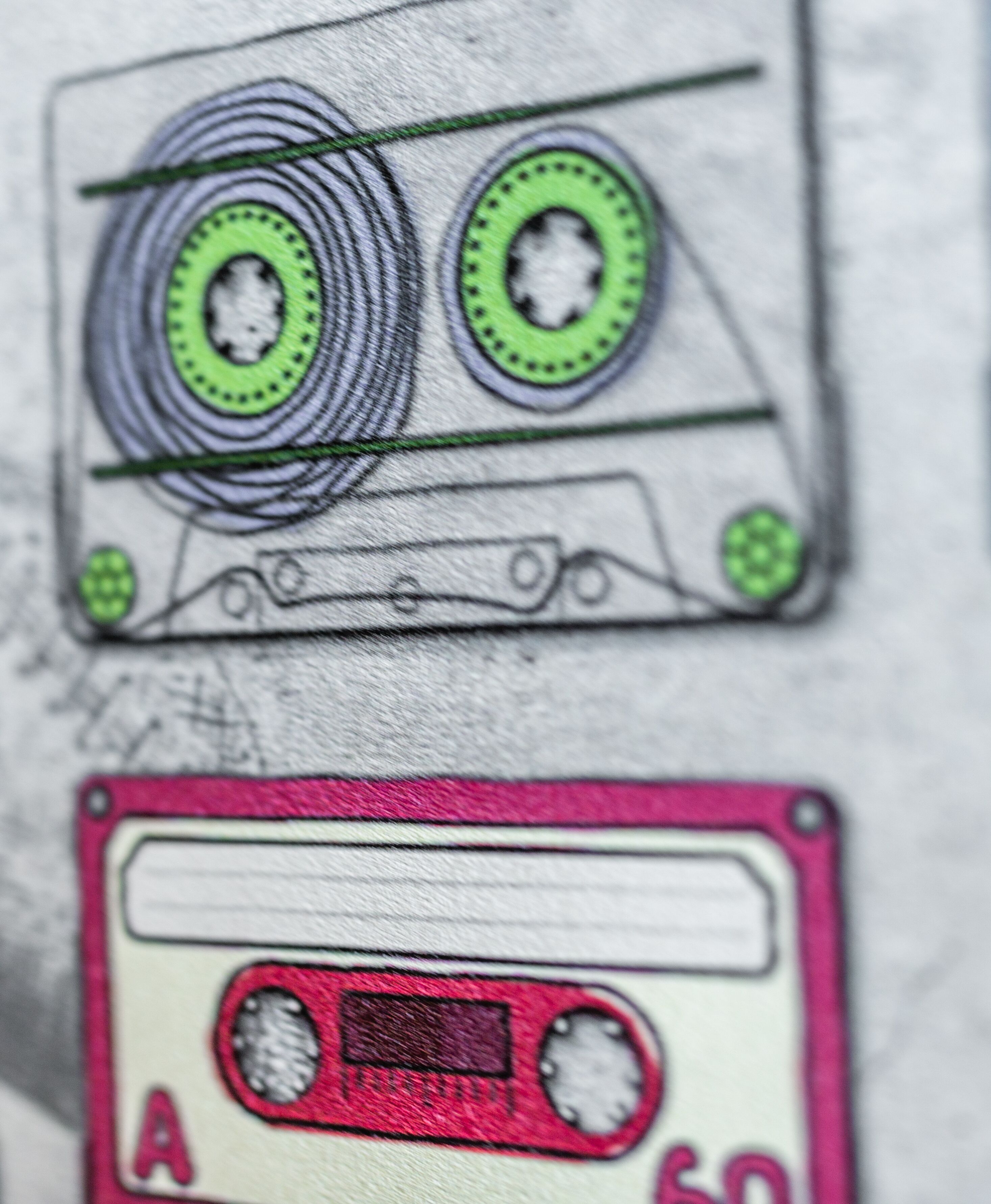 A close-up of two cassette tapes, one with a green reel and the other with a red label.