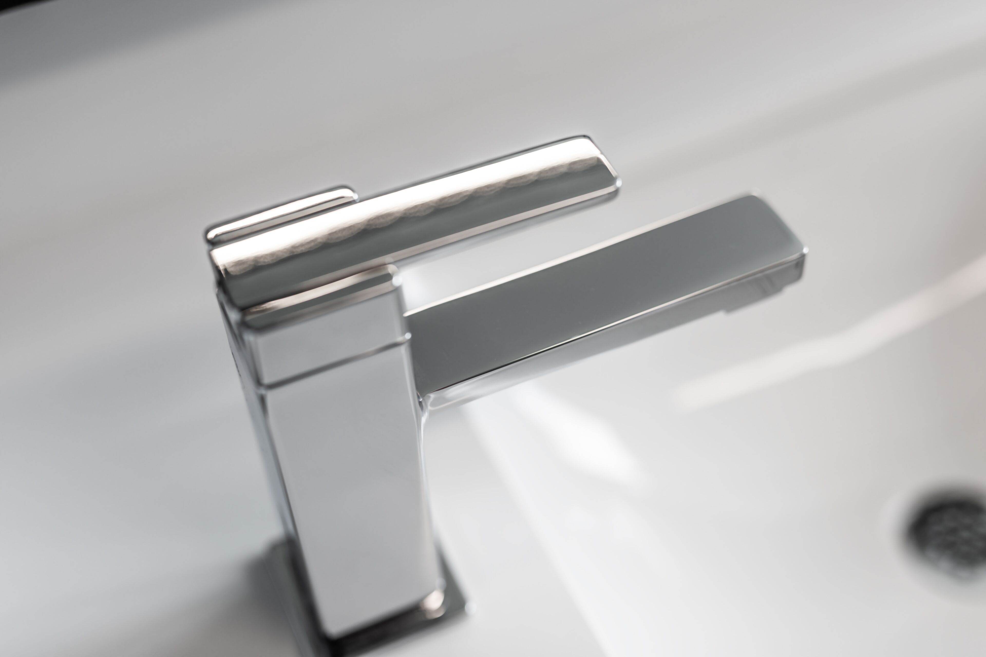 A chrome faucet with a single lever handle on a white sink.