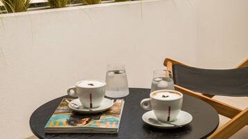 A small round table with two white cups, a glass of water, and a magazine.