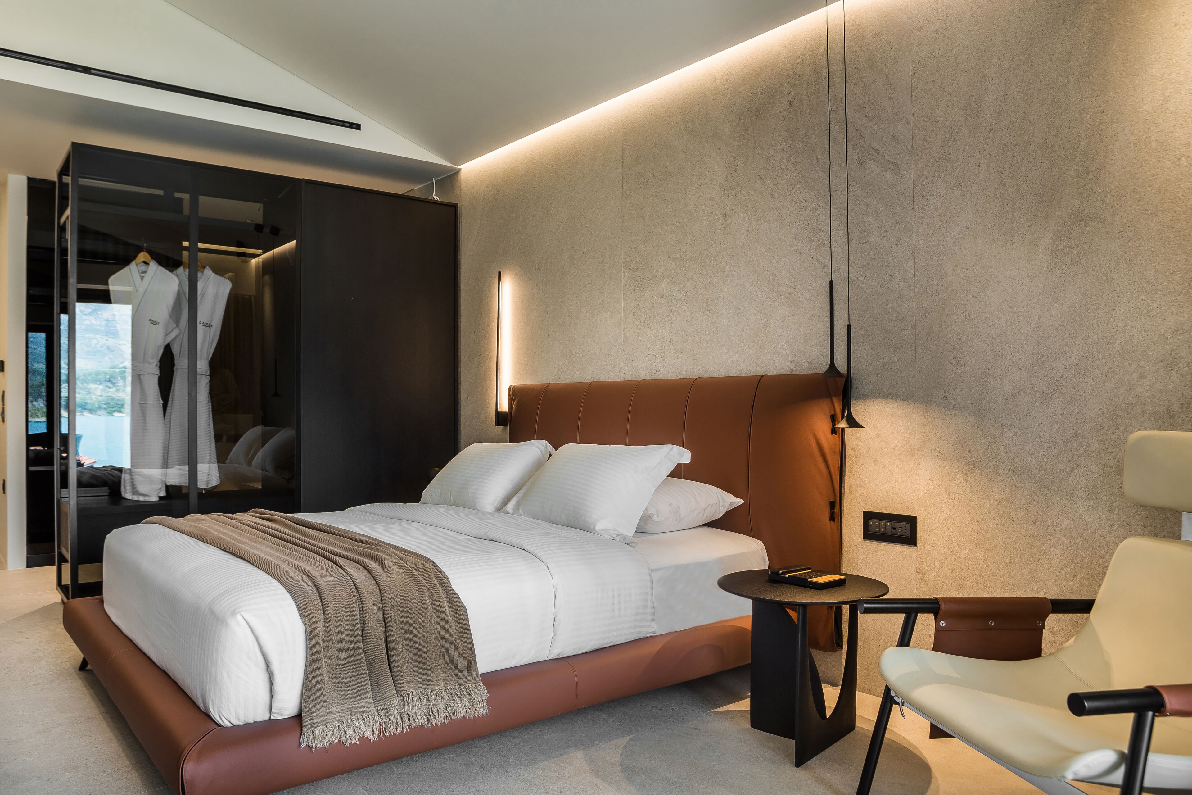 A modern bedroom with a large bed, bedside table, and a chair.