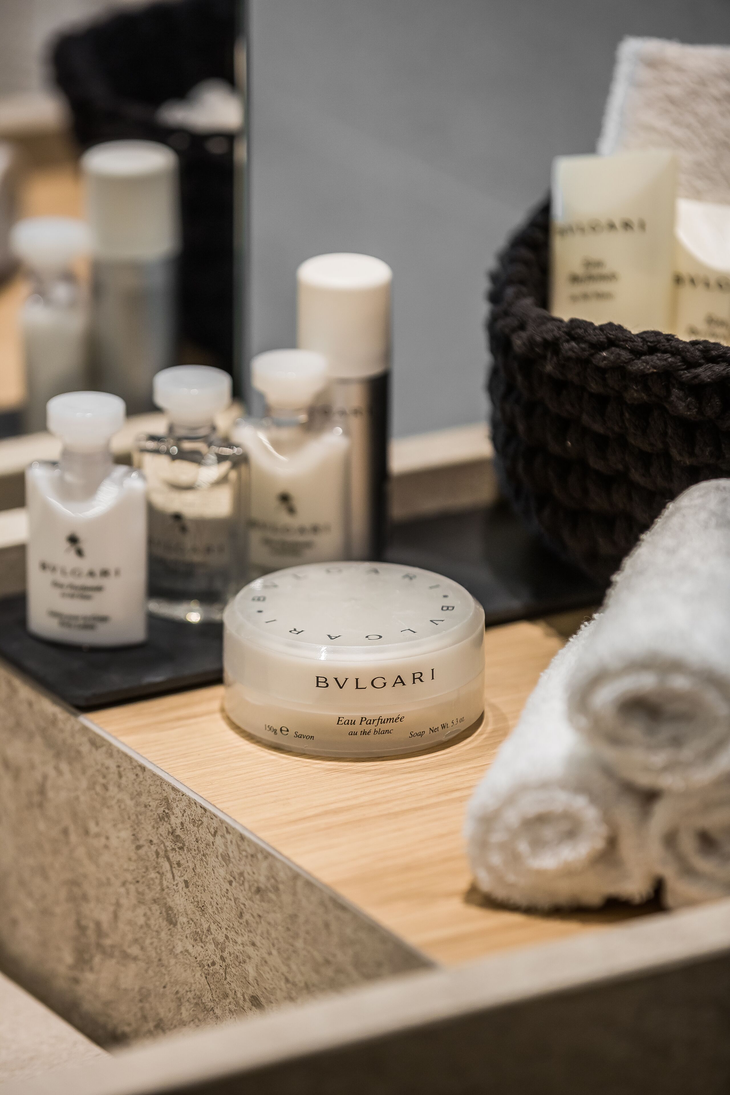 A bathroom vanity with toiletries including a soap bar, bottles, and a towel.