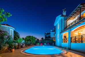 A pool area with a clear blue pool, surrounded by a stone wall and potted plants. - Infinity Flora Villa (Fethiye)