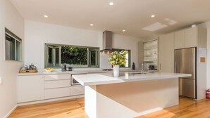 A modern kitchen with a large island, white cabinetry, and a stainless steel refrigerator.
