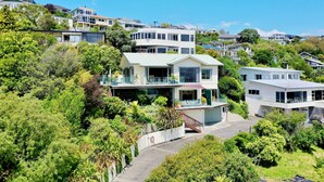 A hillside residential area with modern houses, lush greenery, and a clear blue sky.