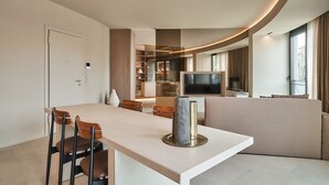 A modern living room with a curved ceiling, a flat-screen TV, a sofa, and a dining area with chairs. - RESIDENZA II LUXURY APARTMENT (Cattolica)