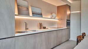 A modern kitchen with a central island, built-in appliances, and minimalist decor. - RESIDENZA II LUXURY APARTMENT (Cattolica)