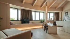 Ein modernes Wohnzimmer mit einer Couch, einem Fernseher und einer Küchenzeile mit Bar.
