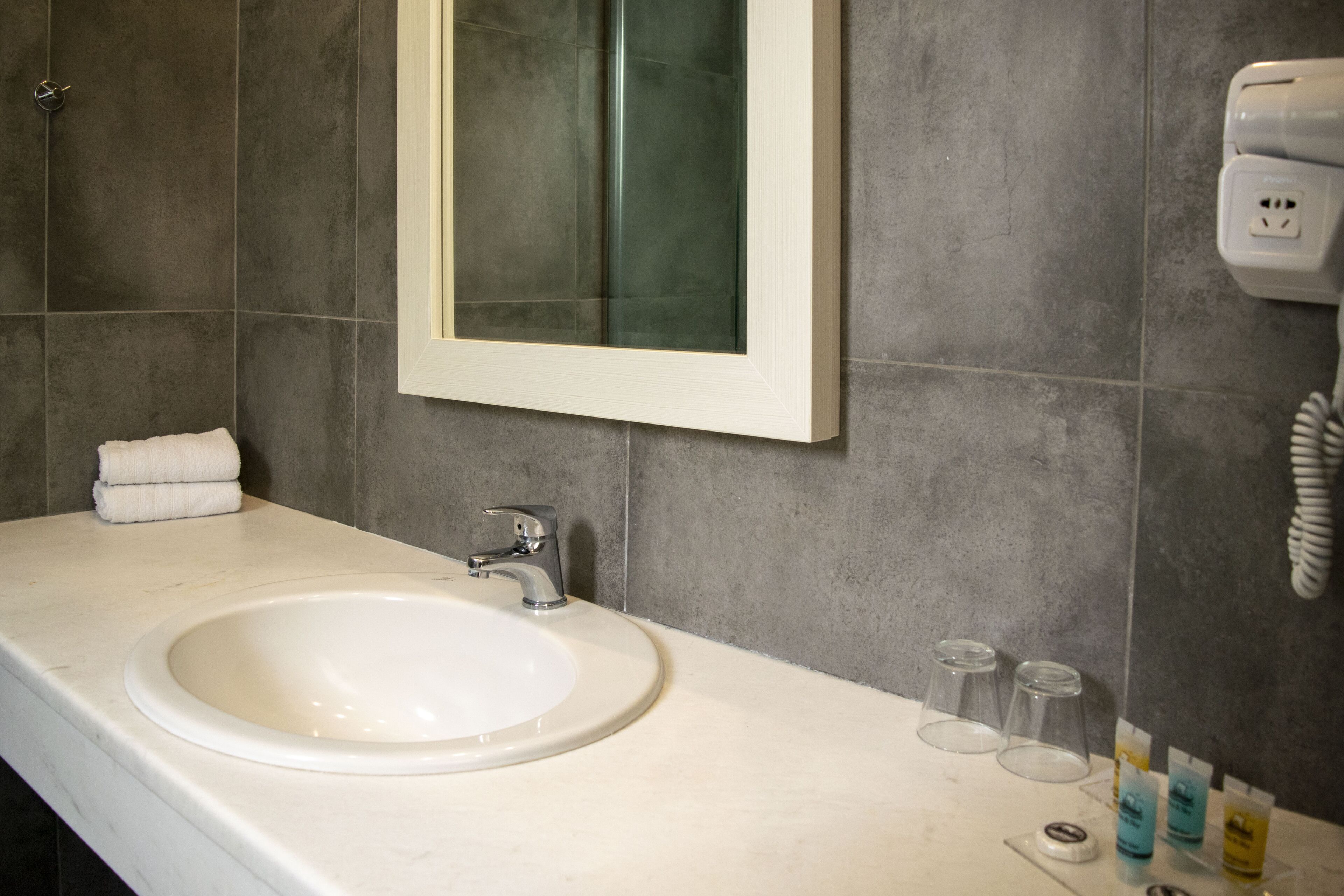 A bathroom with a white sink, a mirror, and a towel rack.