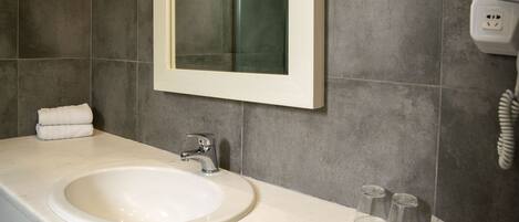 A bathroom with a white sink, a mirror, and a towel rack.