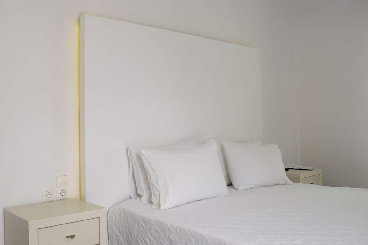 Een strak ingerichte hotelkamer met een groot bed, een nachtkastje en een bedtafel.