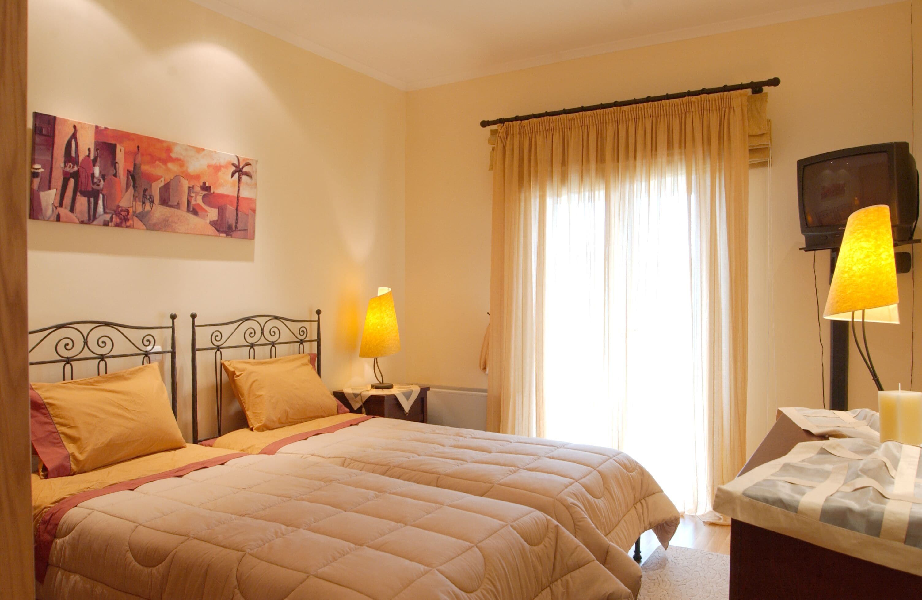 Een hotelkamer met een groot bed, twee bedlampen, een televisie en een schilderij aan de muur.
