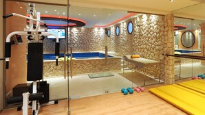 Ett gym med träningsutrustning, en massagebänk och en vägg av sten.