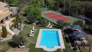 En bostadsfastighet med en swimmingpool, en tennisbana och en vackert anlagd trädgård.