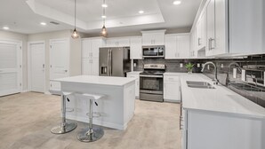 A modern kitchen with white cabinetry, stainless steel appliances, and a central island with bar stools. - 3bd/2ba condo close to Disney, Storey Lake (Kissimmee)