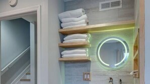 Una cocina compacta con lavavajillas integrado, una encimera de madera y una lámpara moderna sobre el fregadero.