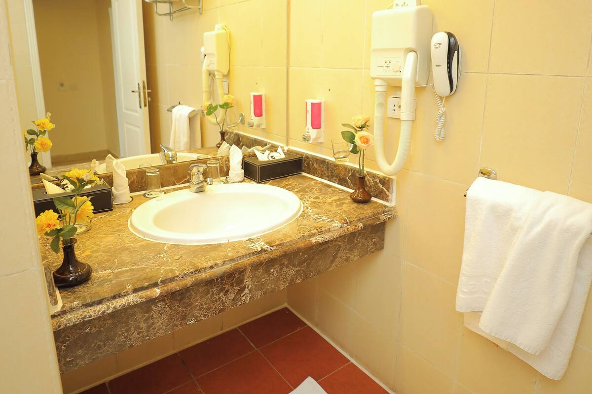 A bathroom with a sink, mirror, towel rack, and a hairdryer on the wall.