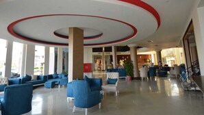 A spacious lobby with blue seating, a red and white ceiling design, and large windows.