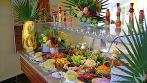 A buffet with various food items and decorative plants.